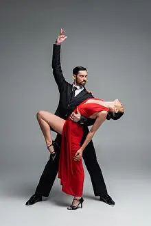 Partners Prints: Elegant man posing while performing tango choreography with partner on grey background