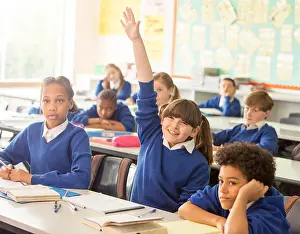 Preteen Prints: Elementary school children in classroom during lesson, smiling girl raising hand