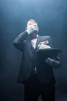 Shocked Prints: emotional magician closing eyes and showing trick with white rabbit in hat