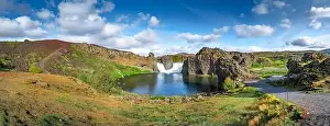 Epic aerial drone panorama view flying over landscape of Hjalparfoss waterfall and lagoon on a sunny day