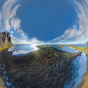 Epic aerial drone view flying over landscape of the black sand beach in Stokksnes on a sunny day