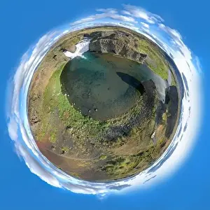 Epic aerial drone view flying over landscape of Hjalparfoss waterfall and lagoon on a sunny day. Little planet panorama