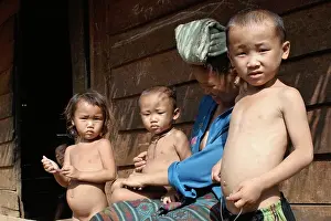 An ethnic Hmong hilltribe family is gathered in front of their home in Luang Prabang Province, Laos