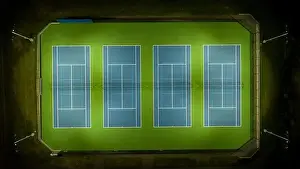 Pickleball Prints: Evening aerial video of outdoor blue tennis courts with pickleball lines with lights turned