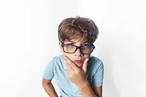 Clever Prints: An exaggerated close up portrait of a funny little boy with glasses making a thinking face