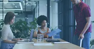 Pulling Prints: Examining African American woman reviewing blue binder at office meeting table