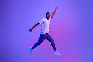 Fluorescent Prints: Excited Funny Black Guy Jumping Up In Neon Light Over Purple Background
