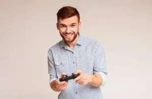 Enjoy Prints: Excited millennial guy playing video games with jpystick