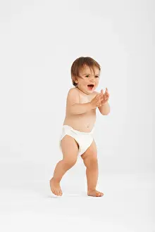 Diaper Prints: Excited toddler taking first steps in white studio