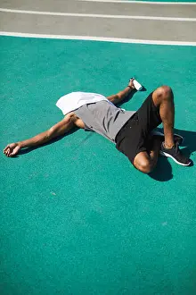 Exhausted Prints: Exhausted black man lying on stadium ground