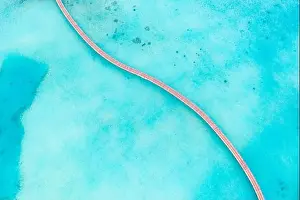 Exotic aerial view of turquoise water with wooden jetty in Maldives islands. Amazing sea lagoon. Tropical ocean water, sunny weather, abstract aerial