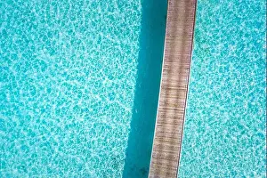 Exotic aerial view of turquoise water with wooden jetty in Maldives islands. Amazing sea lagoon. Tropical ocean water, sunny weather, abstract aerial