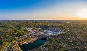 Dump Prints: Extraction of minerals with the help of special equipment near a small lake in the warm evening light in picturesque
