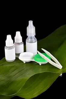 Medication Prints: Eye drops and lenses on leaf on black background