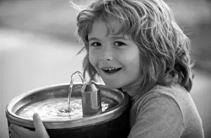 Thirsty Prints: Face close up portrait of kid drinking water from outdoor water fountain outdoor