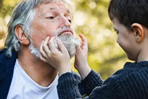 Interact Prints: Faceless little child touching face with gray beards of senior man while looking at each other on blurred background