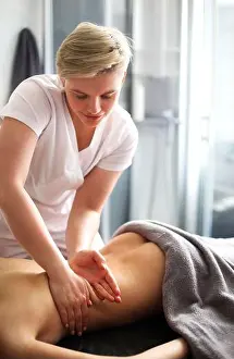 Muscle Prints: Faceless master giving massage of back and shoulder muscles to anonymous woman lying on table in spa salon