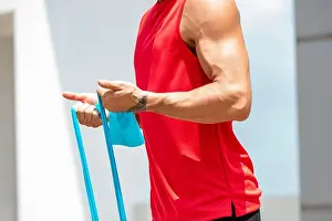 Work Out Prints: Faceless muscular athletic man doing bicep curl exercise with resistance band in the open air