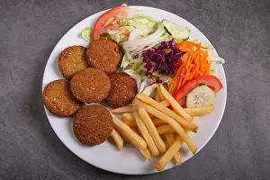 Falafel plate with salad and french fries isolated on rustic background