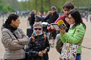 British English Prints: A family checking out London locations in a Tourist guild book, London, United Kingdom