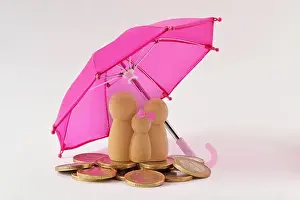 Protecting Prints: Family and pile of coins under umbrella - Concept of family and financial protection