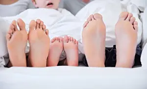 Family resting day. Shot of an unrecognizable family laying barefoot on a bed at home