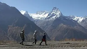 Family walks on background of mountain valley with snowy peaks