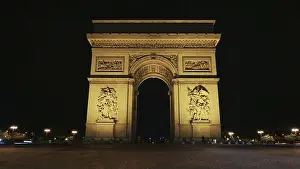 From Below Prints: The famous Champs-Elysees arch illuminated with bright lights at night and street in foreground