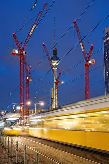 Building Site Prints: The famous Television Tower of Berlin at night with red construction cranes and a motion blurred tramway