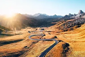 Fantastic aerial view on winding road in autumn mountain valley at sunset