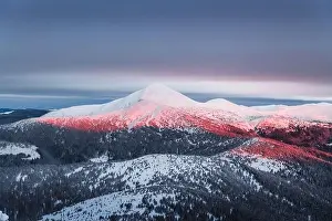 Fantastic orange winter landscape in snowy mountains glowing by sunlight. Dramatic wintry scene with snowy trees. Christmas holiday background