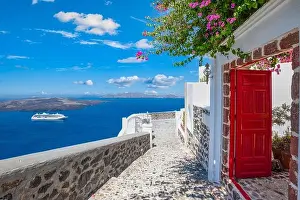Fantastic travel background, Santorini urban landscape. Red door or gate with stairs and white architecture under blue sky. Idyllic summer vacation