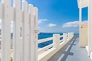 Fantastic travel background, Santorini urban landscape. Red door, gate with stairs white architecture under blue sky. Idyllic summer vacation luxury