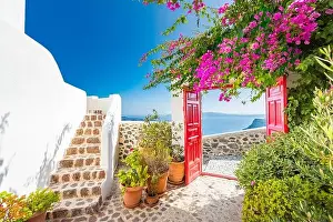 Fantastic travel background, Santorini urban landscape. Red door or gate with stairs and white architecture under blue sky. Idyllic summer vacation