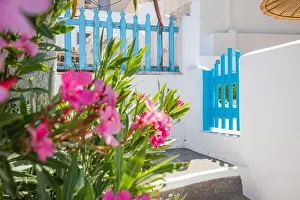 Fantastic travel background, Santorini urban street landscape. Blue door or gate stairs and white architecture under sunny sky. Amazing summer scene