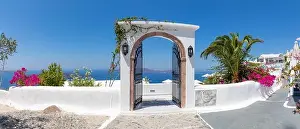 Fantastic travel panorama, Santorini urban street landscape. Door or gate stairs and white architecture under sunny sky. Amazing summer vacation