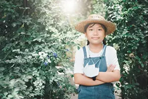 Overalls Prints: Farmer girl wearing denim overalls with hat and hanging a mask in the vegetable garden