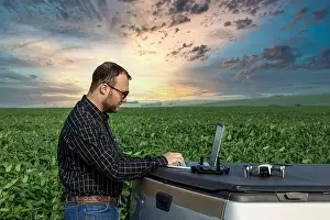 Farmer standing in soybean field looking at notebook and drone