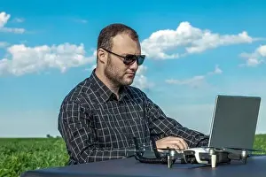 Inspect Prints: Farmer standing in soybean field looking at notebook and drone