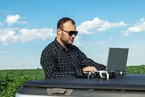 Inspect Prints: Farmer standing in soybean field looking at notebook and drone