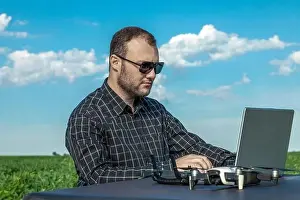 Inspect Prints: Farmer standing in soybean field looking at notebook and drone