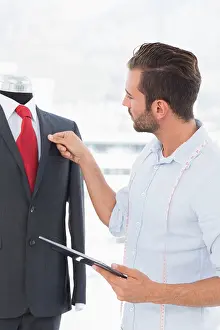 Stylist Prints: Fashion designer with digital tablet looking at suit on dummy