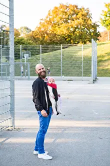 Babyhood Prints: Father with baby girl in baby carrier on playing field