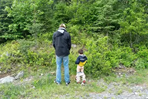 father and son peing in the woods