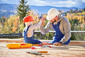 Carpenter Prints: Father with toddler son building wooden frame house