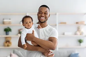 Childcare Prints: Fatherhood. Portrait Of Happy Young Black Man Holding His Adorable Infant Baby