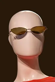 Imitation Prints: Featureless mannequin head with sunglasses and an orange tee-shirt against black background