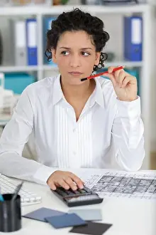 Compass Prints: female architect working on blueprint plans and calculator