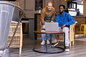 Listening Prints: Female barista wearing apron pointing at laptop while African American man watching in coffee shop