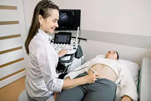 Expecting Prints: Female doctor performs ultrasound examination of pelvic organs of her female patient for diagnostic early pregnancy